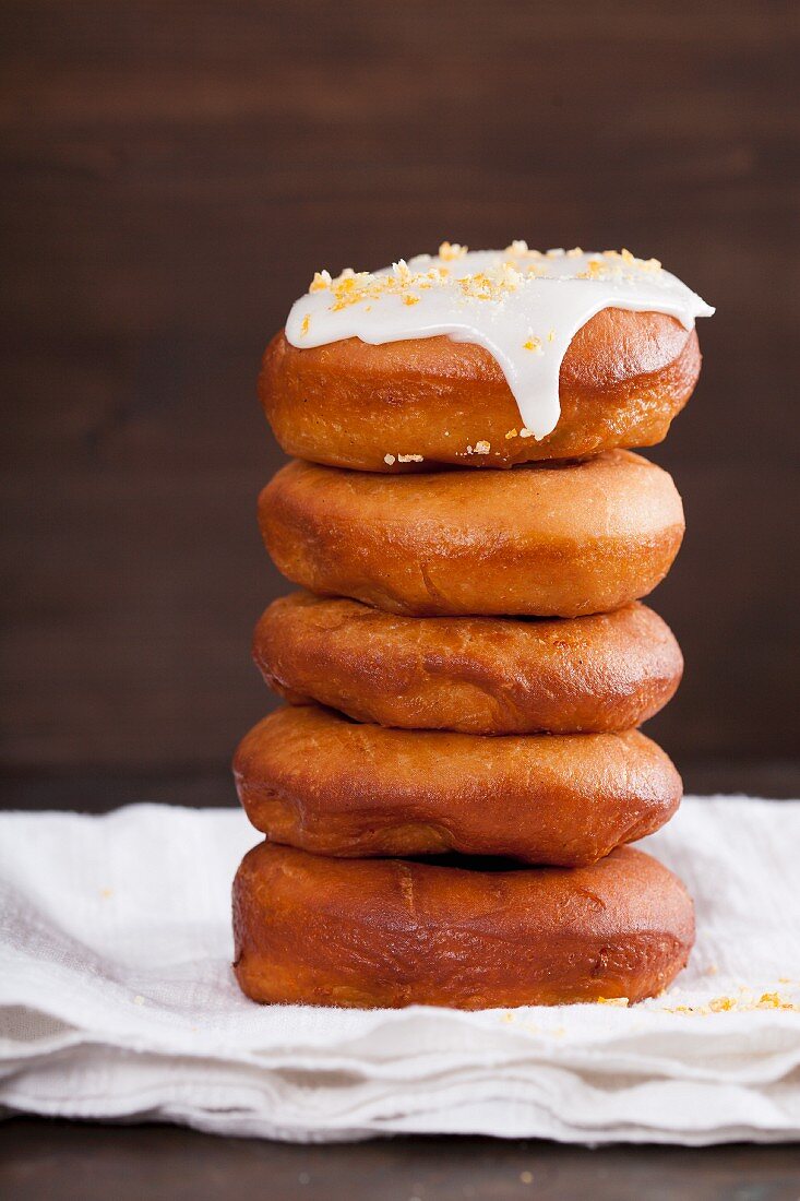 Donuts with a lemon glaze and candied orange pieces, stacked