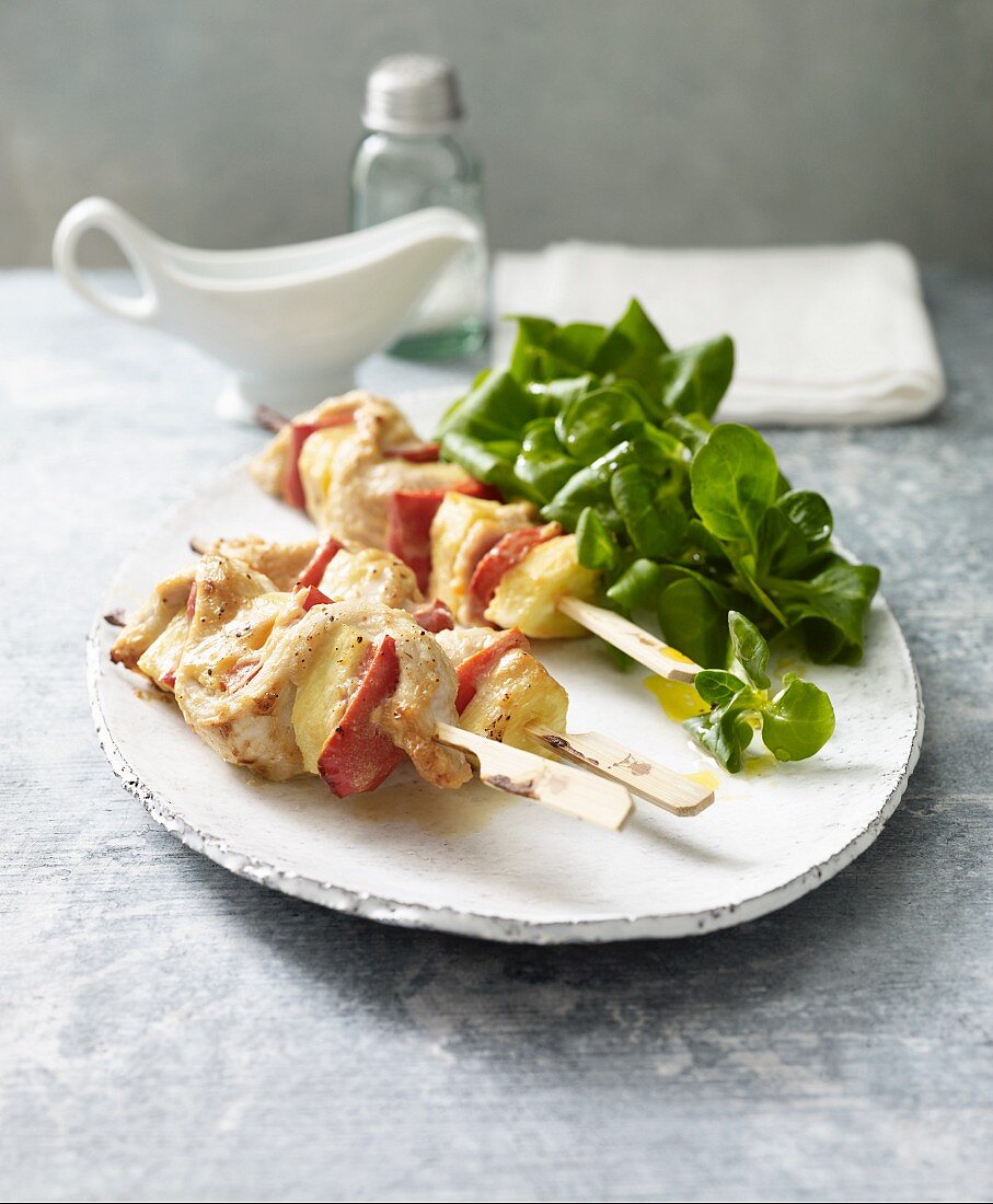 Lactose-free turkey skewers with pineapple and red pepper, served with lamb's lettuce