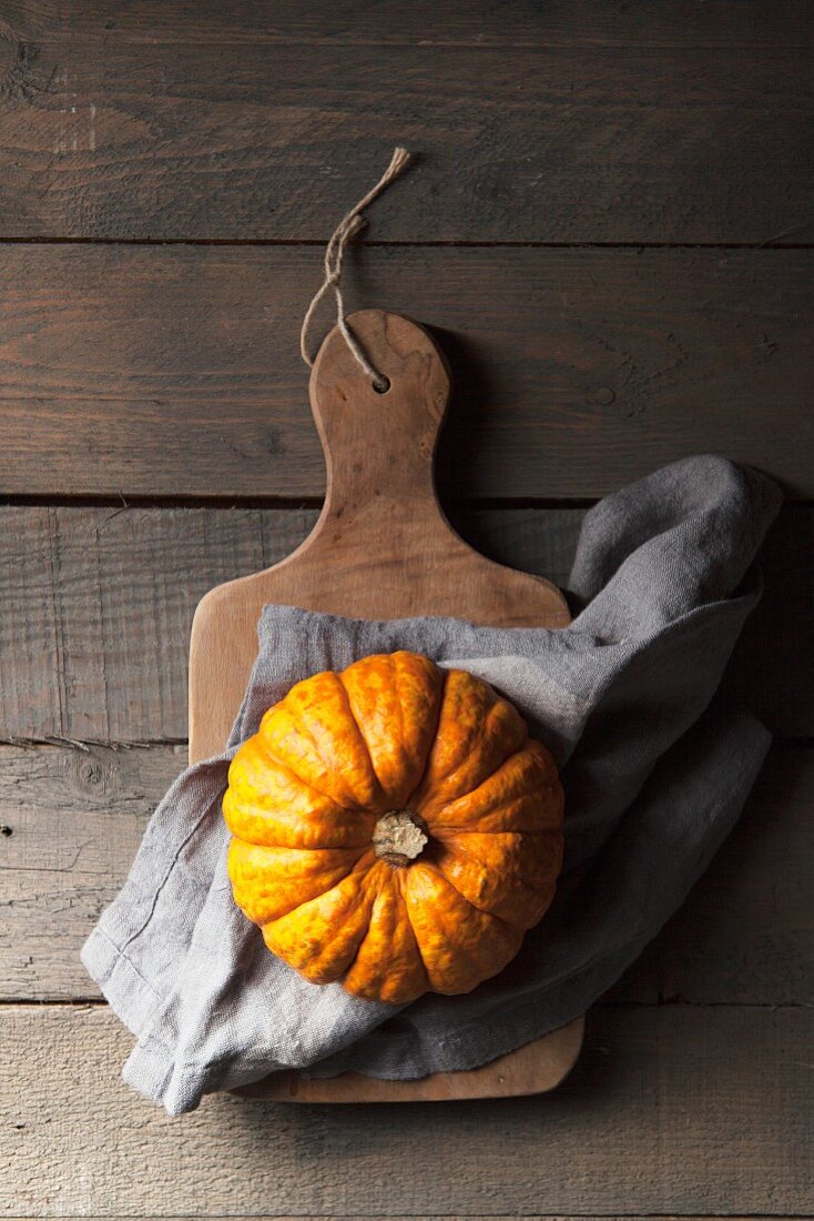 A munchkin pumpkin on a rustic wooden background with a grey linen napkin