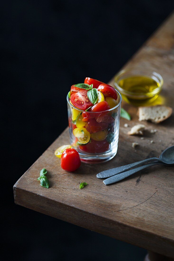 Fresh cherry tomato salad with basil and olive oil served in a glass