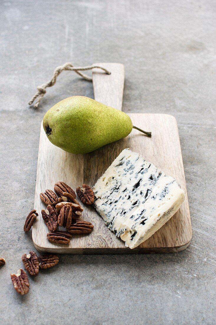 Roquefort, pecan nuts and a fresh pear on a wooden board