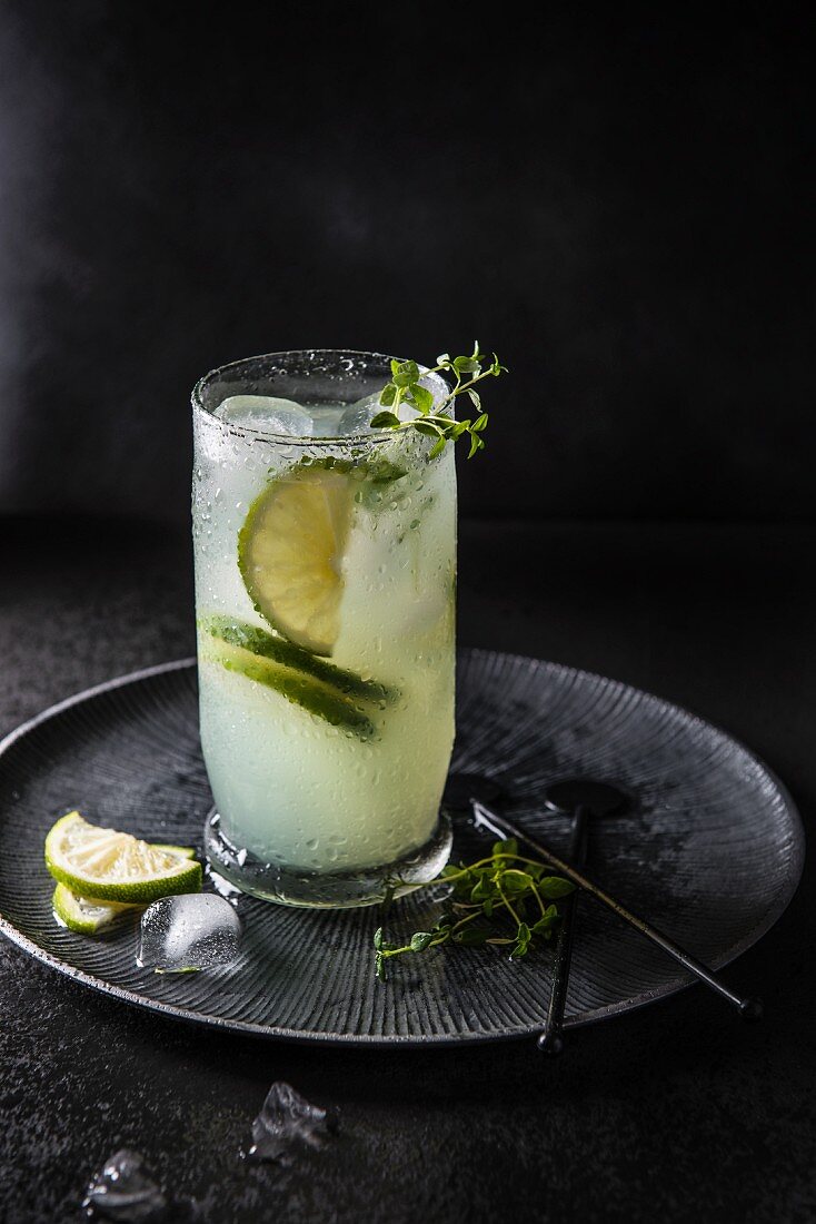 Cocktail mit Bitter Lemon, Limette, Gin, Thymian und Eiswürfeln