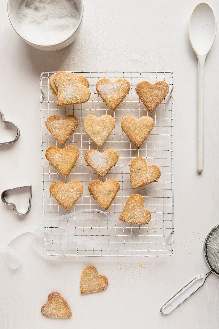 Heart-shaped butter biscuits coated in sugar on a cooling rack