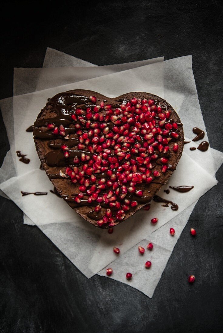 Heart-shaped chocolate cake with chocolate glaze and pomegranate seeds