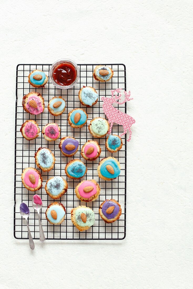 Biscuits with strawberry jam and icing (poppy seeds and almonds as decoration)