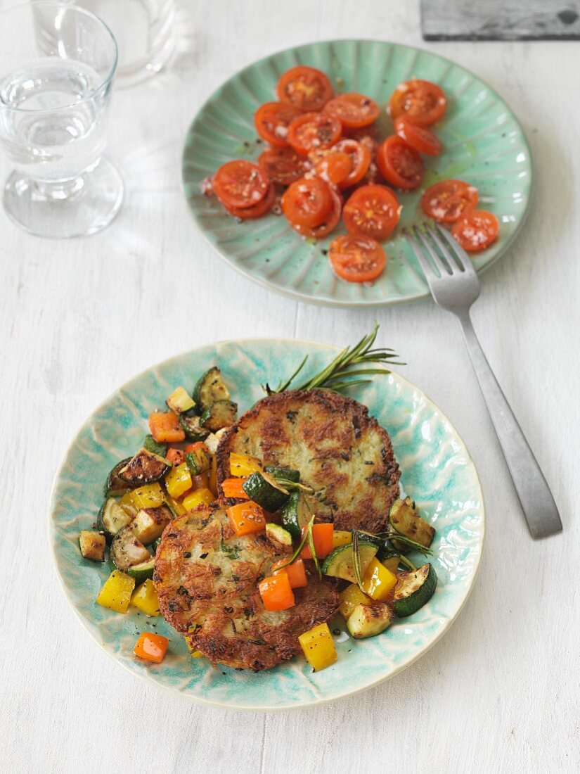 Vegan herb potato cakes with rosemary vegetables and tomato salad