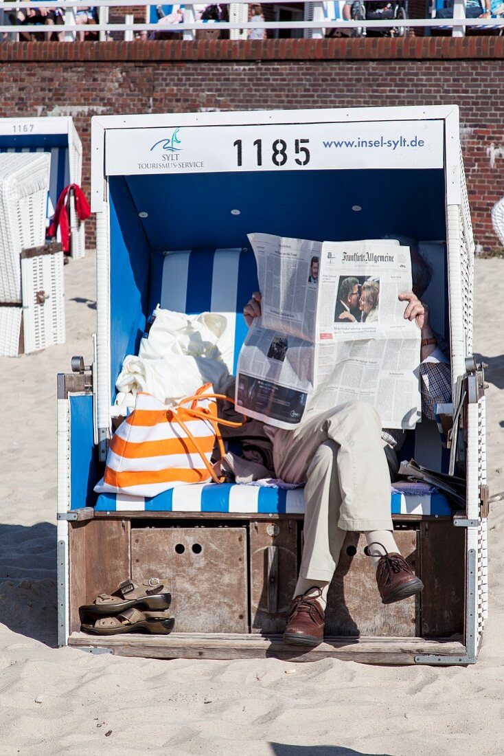 Person mit Zeitung am Strand von Westerland, Sylt, Deutschland