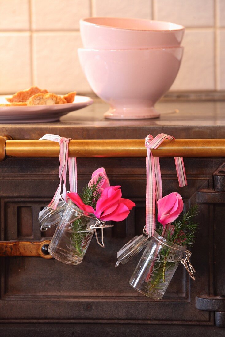 Cyclamen and juniper sprigs in preserving jars hung from old stove