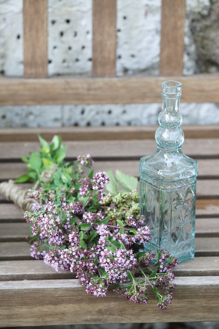Bunch of flowering oregano next to small glass carafe
