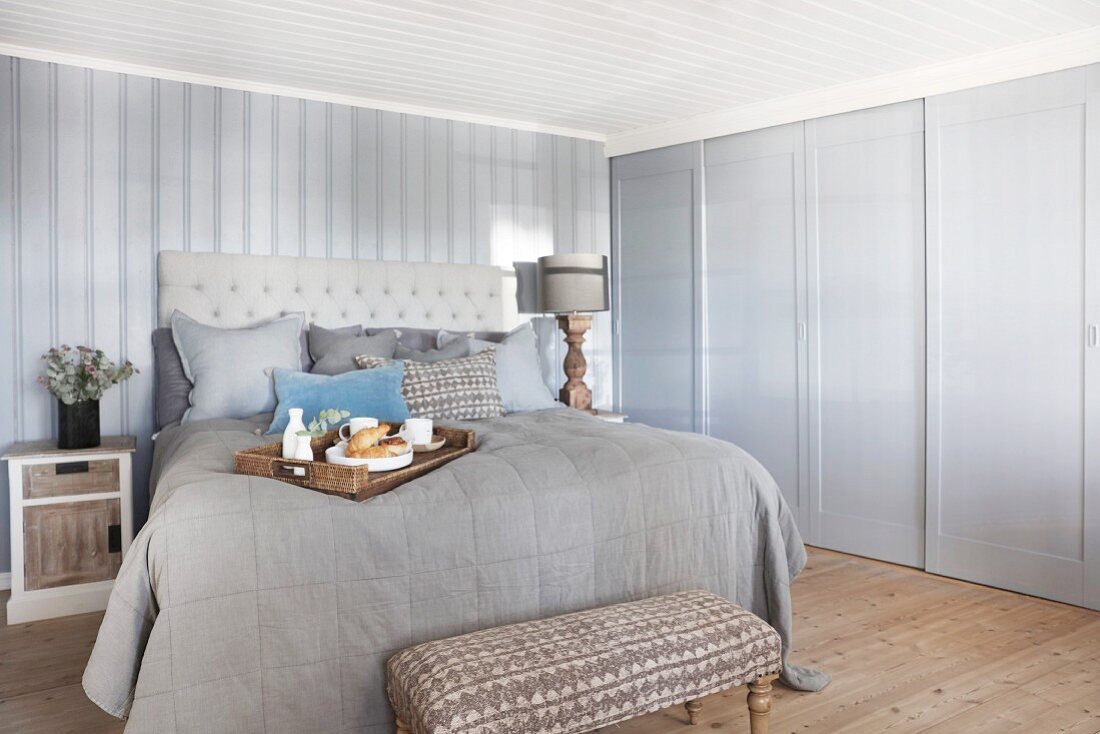 Elegantes Landhaus-Schlafzimmer mit Frühstückstablett auf Doppelbett vor Einbauschrank