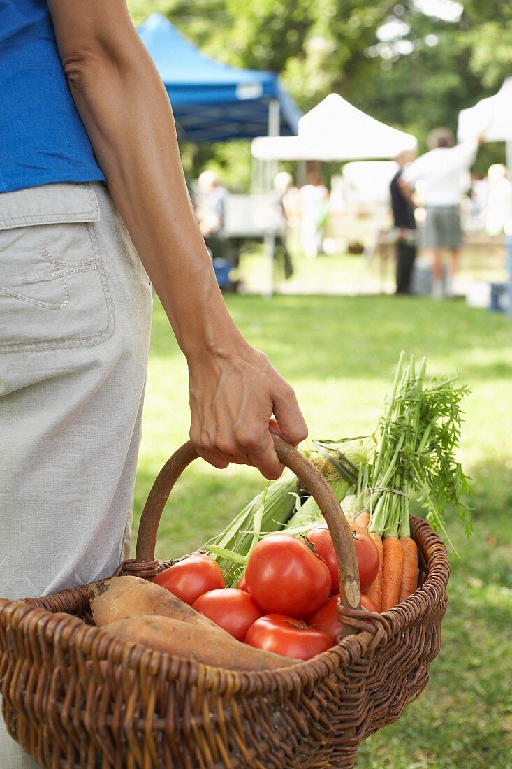 Frau trägt Korb mit frischem Gemüse