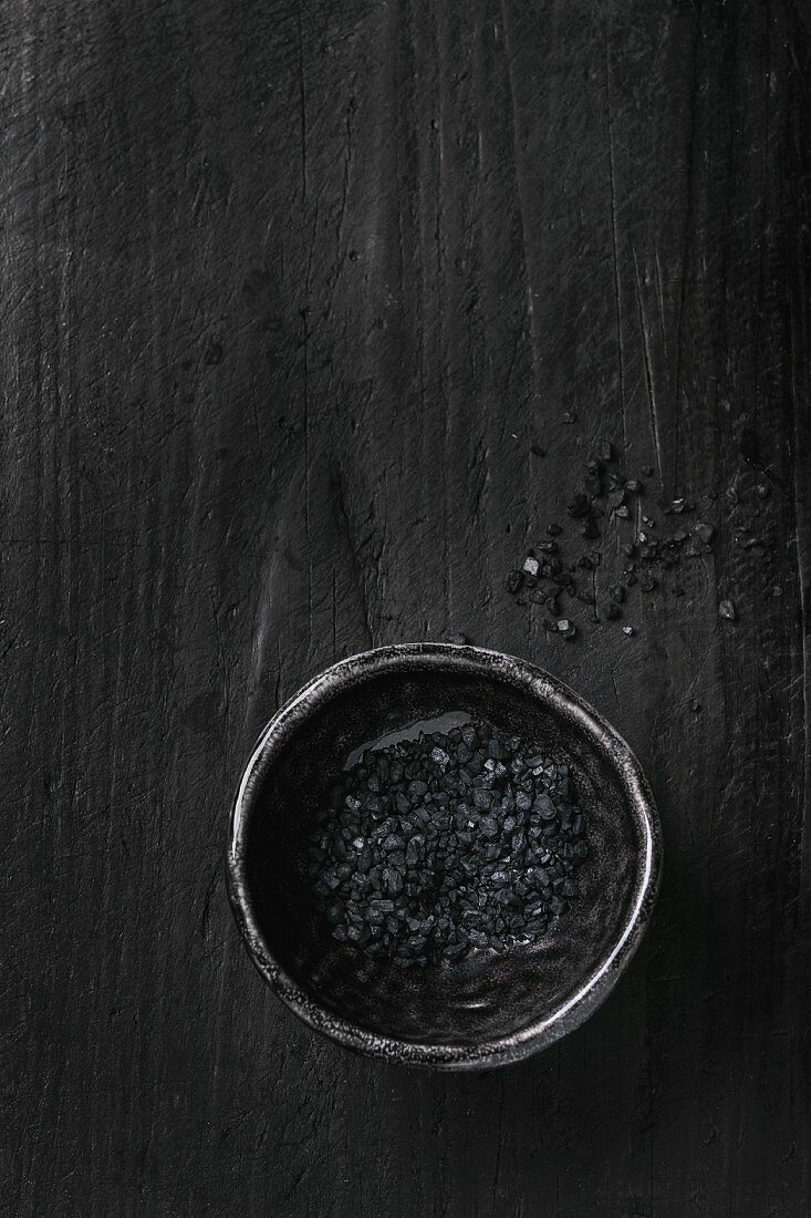 Eine Schale schwarzes Salz auf schwarzem Hintergrund