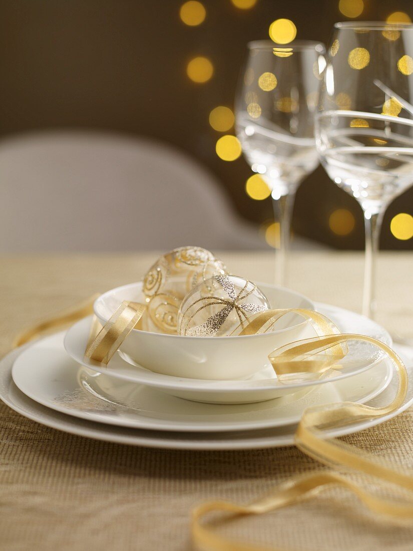 A Christmas table setting with gold ribbon and baubles