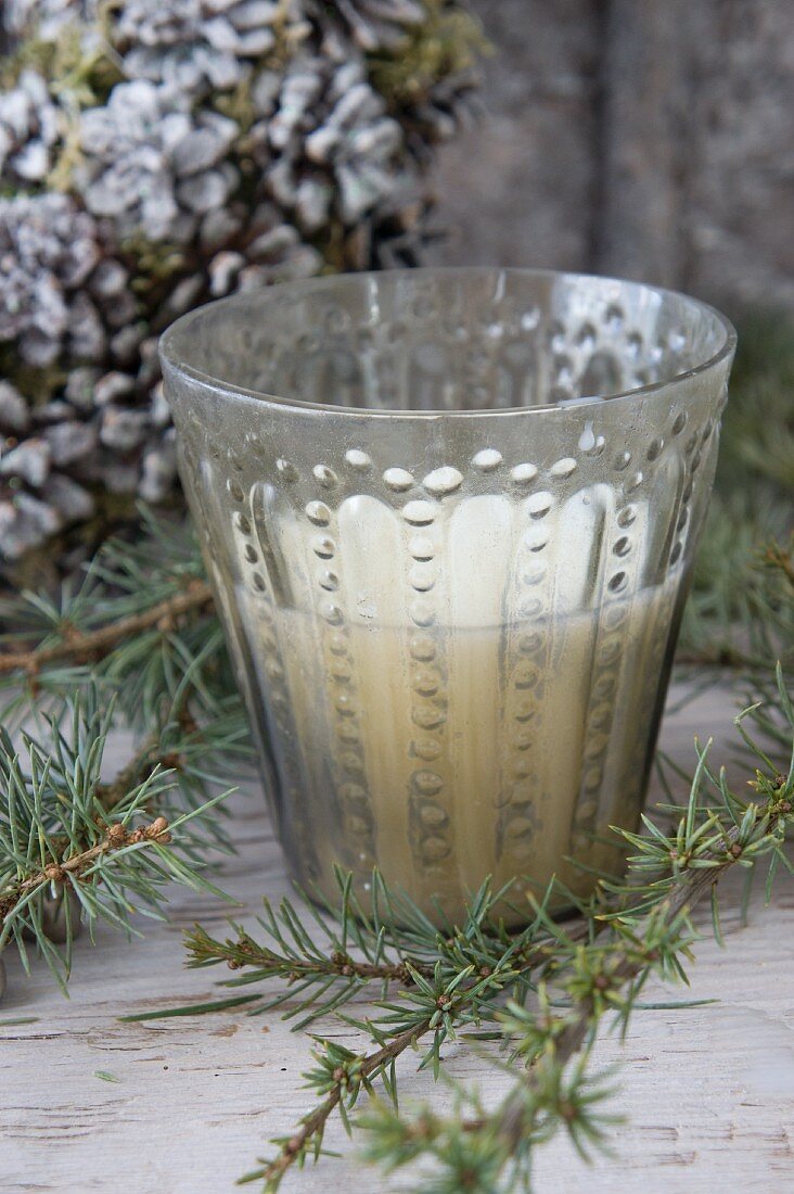 Vintage-style patterned glass candle lantern amongst larch twigs
