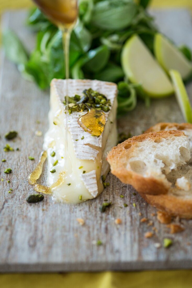 Brie with honey, pistachios, a baguette, lambs lettuce and apples