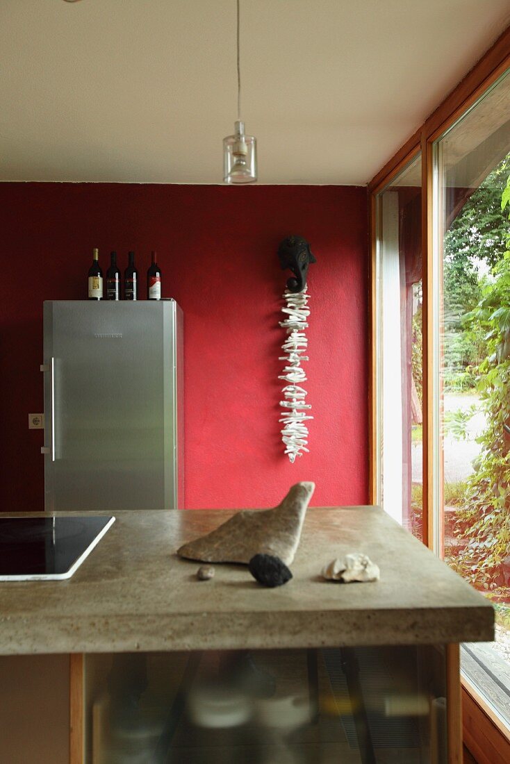 Island counter with concrete worksurface in front of red wall