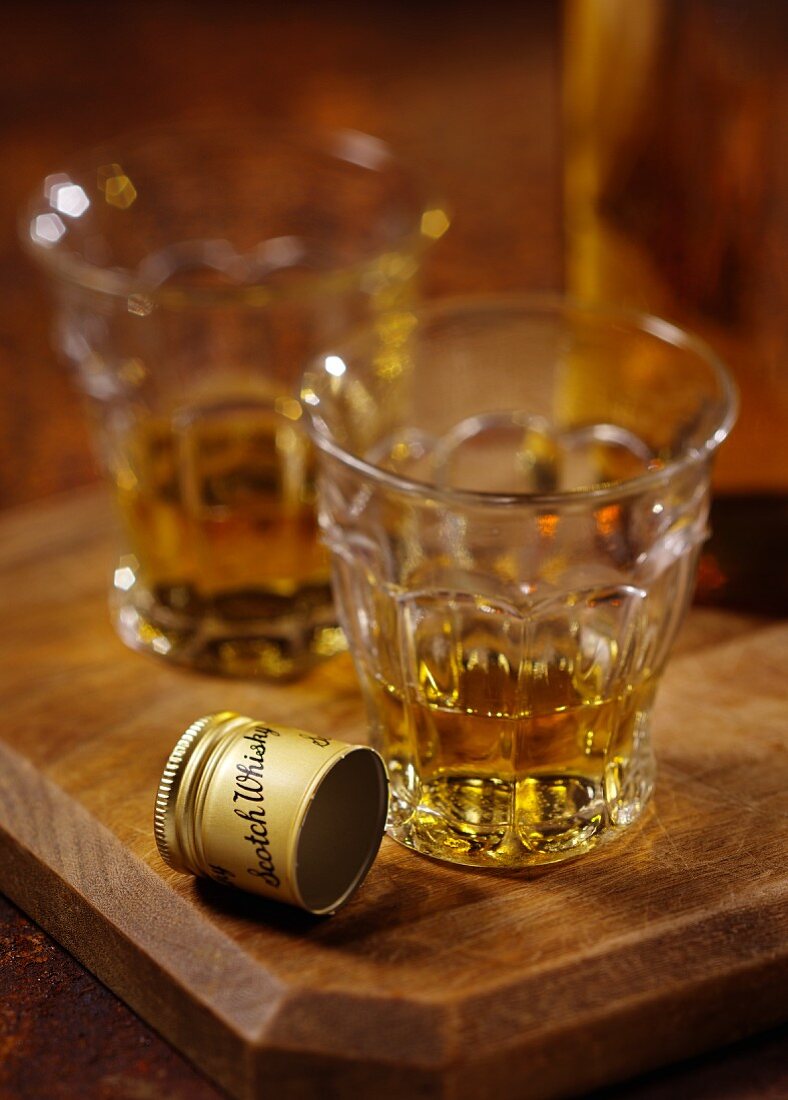 Two glasses of Scotch whisky on a wooden board