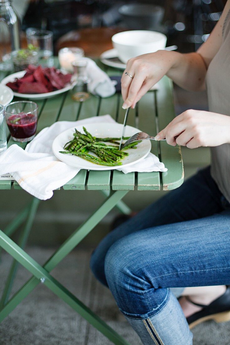 Frau isst blanchierten grünen Spargel