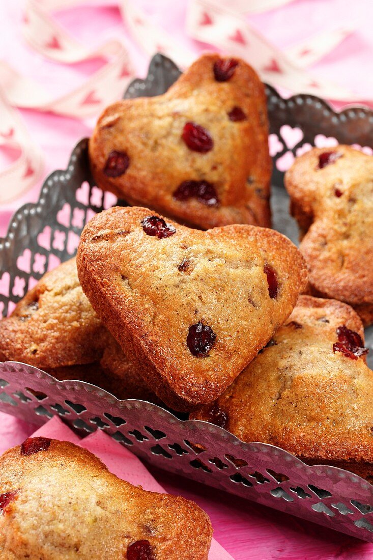 Heart shaped muffins in a metal basket on a pink background with pink ribbon with heart pattern