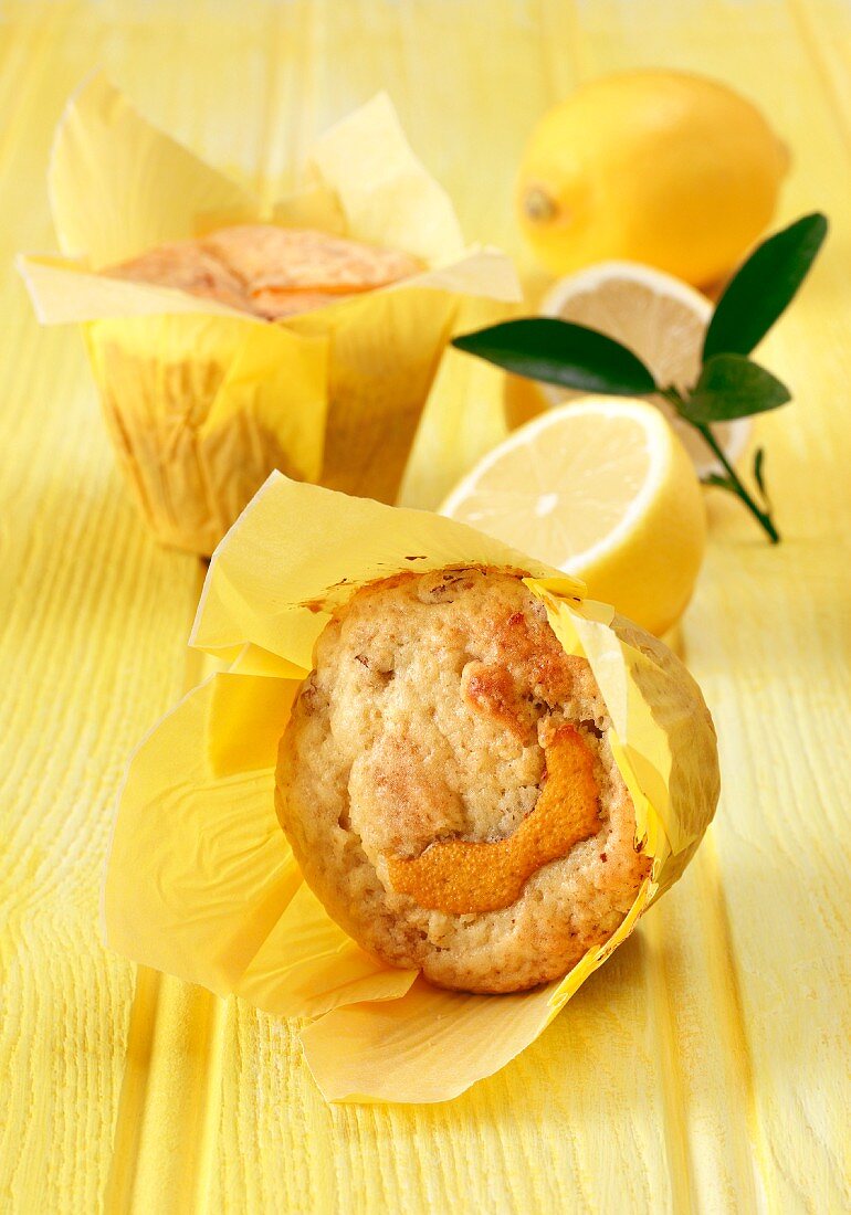 Lemon and sultana muffins on a yellow background with fresh lemons and leaves