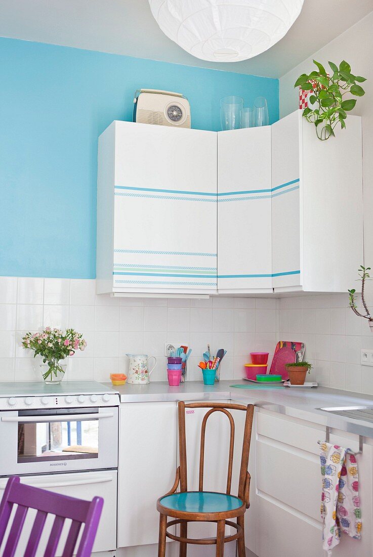 Wall units with striped fronts on turquoise wall in white fitted kitchen