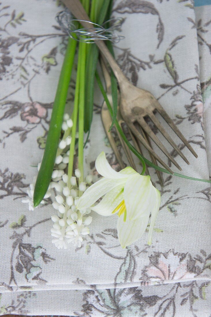 Stoffserviette mit floralem Motiv, Vintage Gabeln und weißen Frühlingsblumen