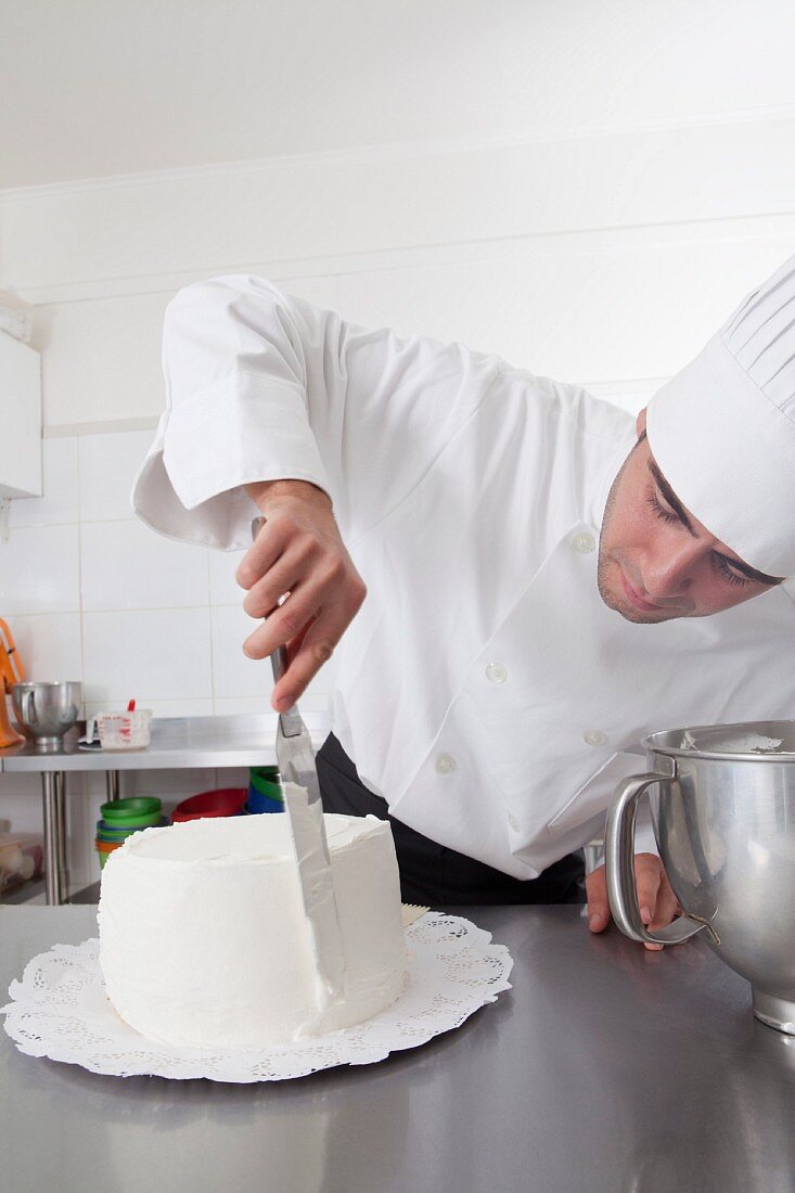 Koch verziert weiße Torte