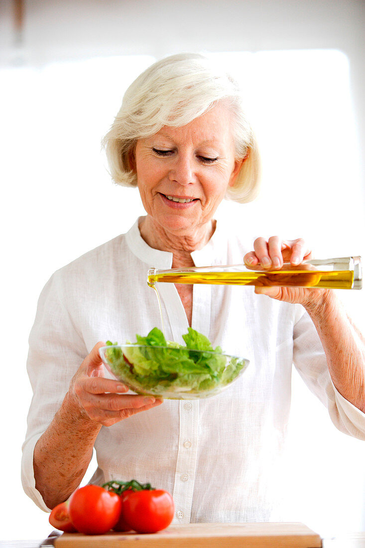 Woman adding olive oil on a salad