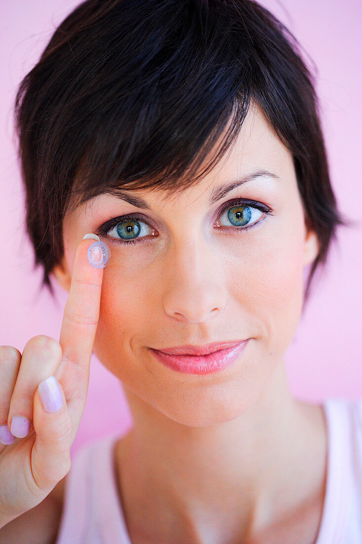 Woman placing coloured contact lens