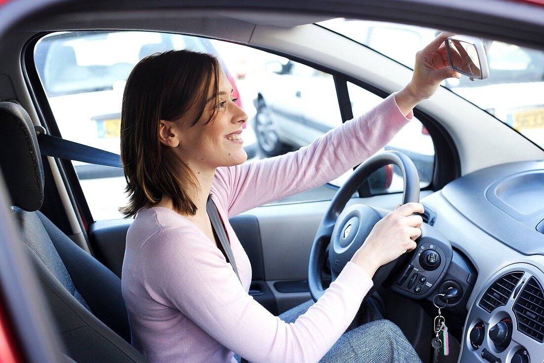 Woman adjusting rear-view mirror