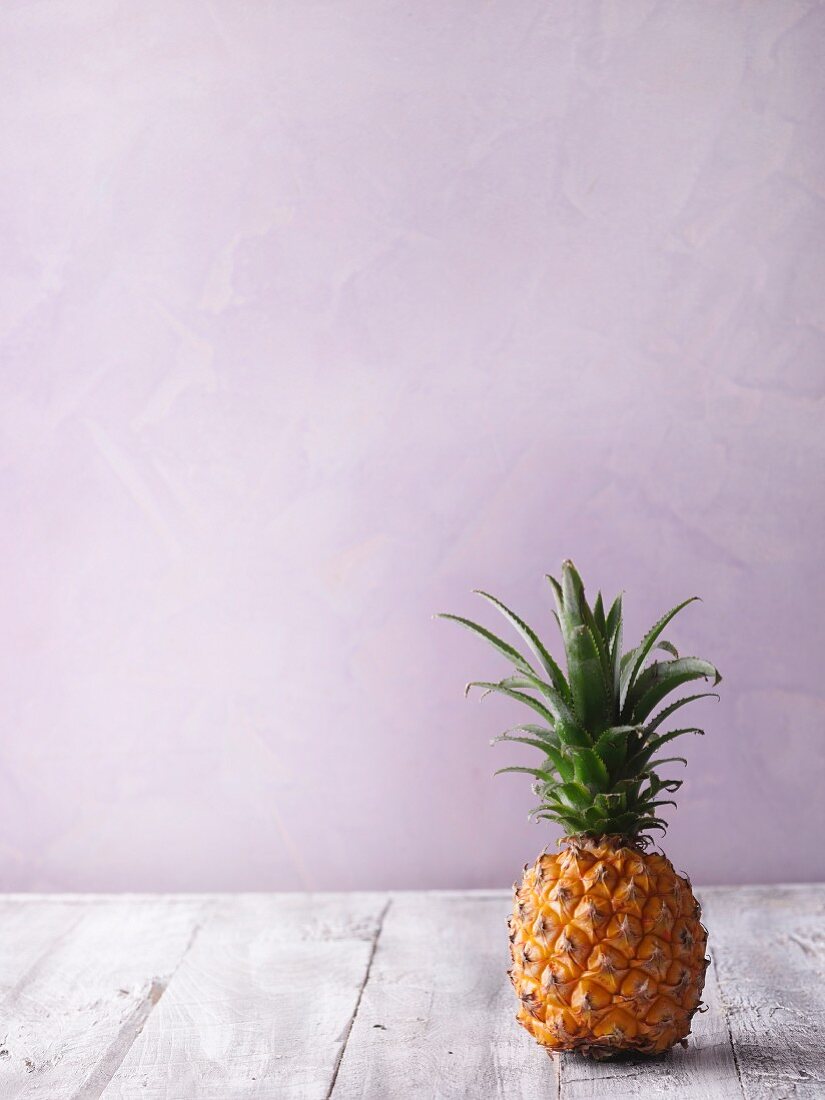 A pineapple on a grey wooden surface