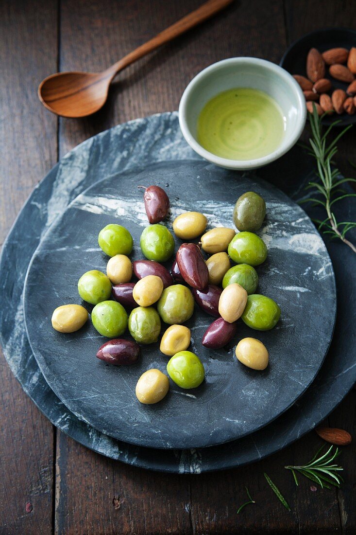 Gemischte schwarze und grüne Oliven mit Mandeln, Olivenöl und Rosmarinzweigen