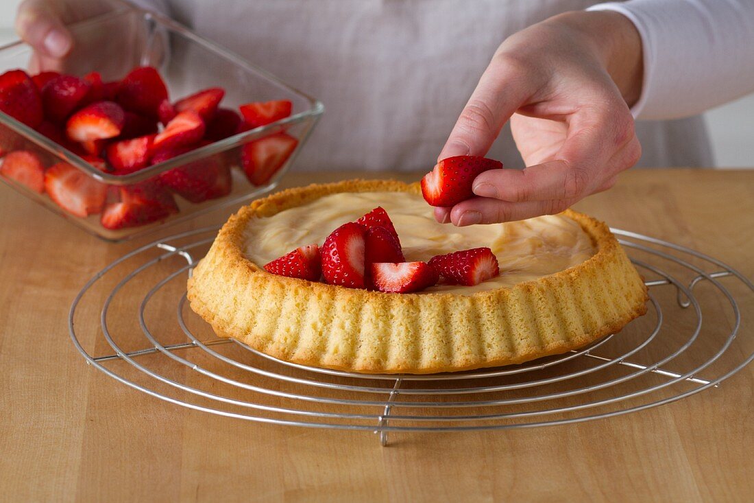 Erdbeertarte mit Vanillepudding zubereiten: Erdbeeren auf der Tarte verteilen