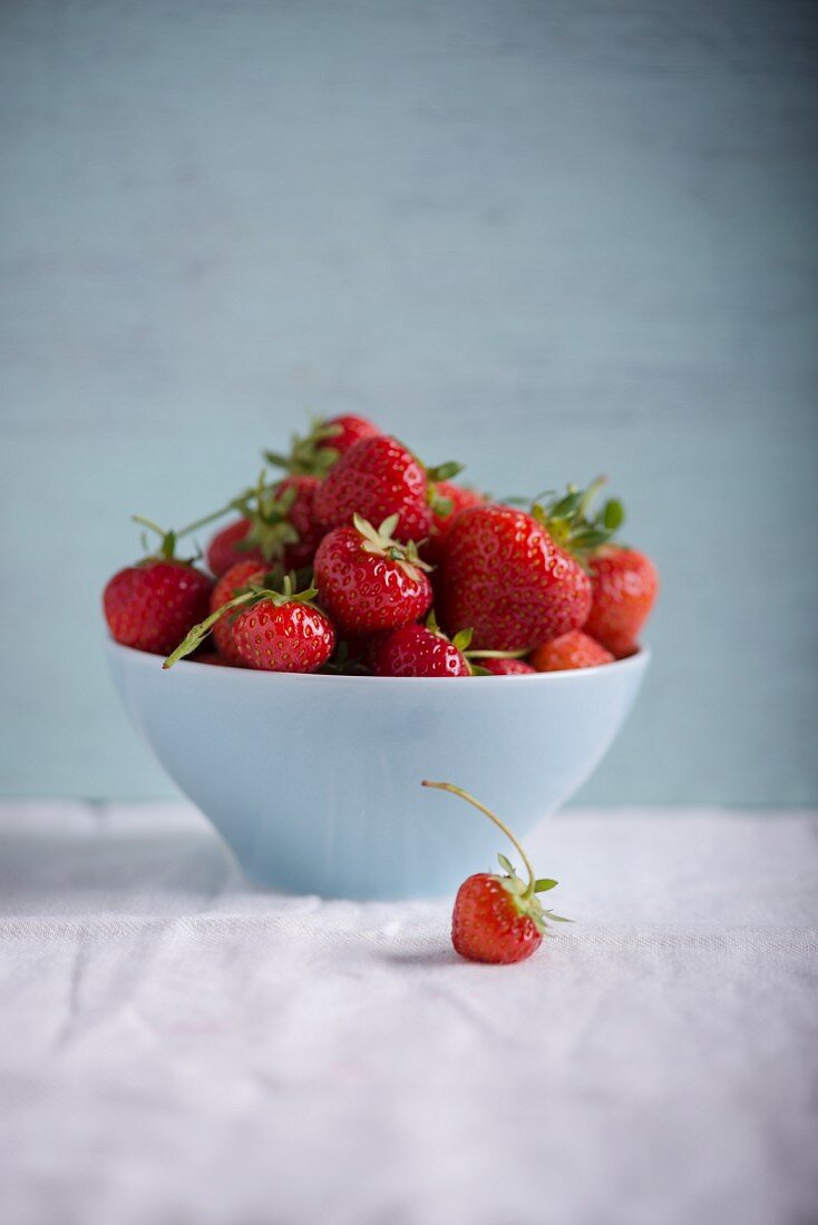 Strawberries in a white bowl on a white tablecloth