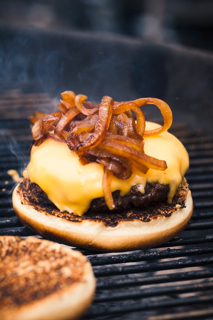 A hamburger with cheese and toasted onions on a grill