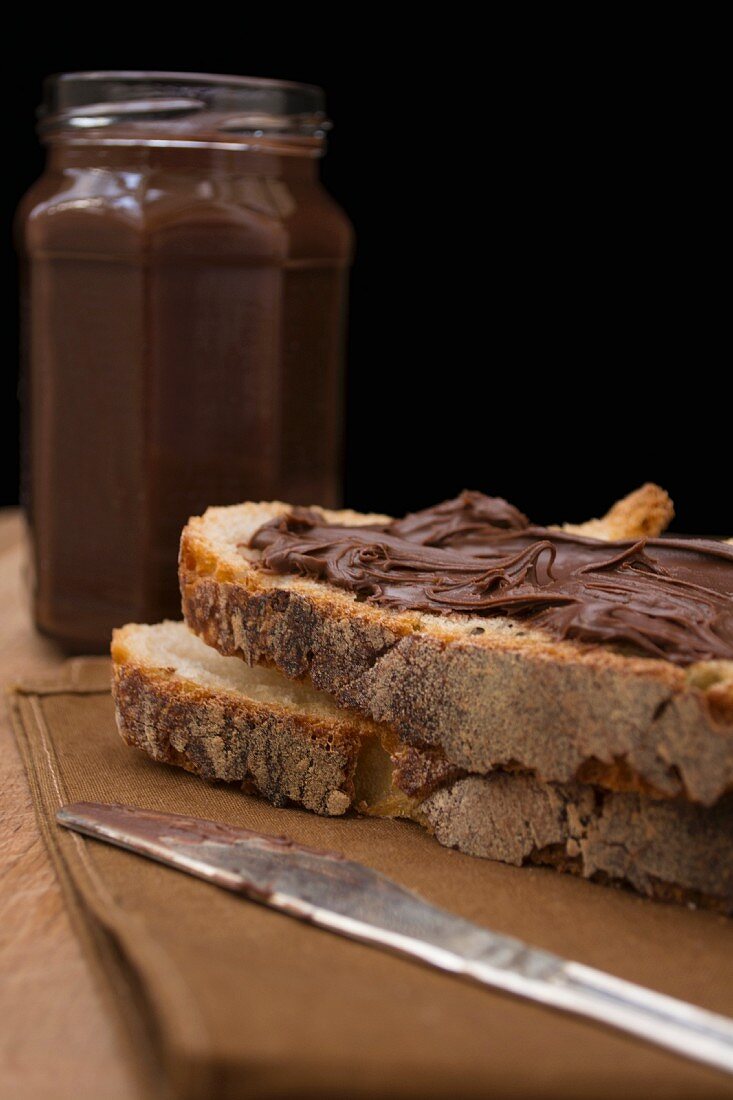 Schokoladenaufstrich im Glas und auf Brot