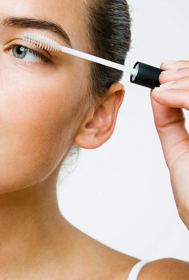 A young woman applying eyelash balm