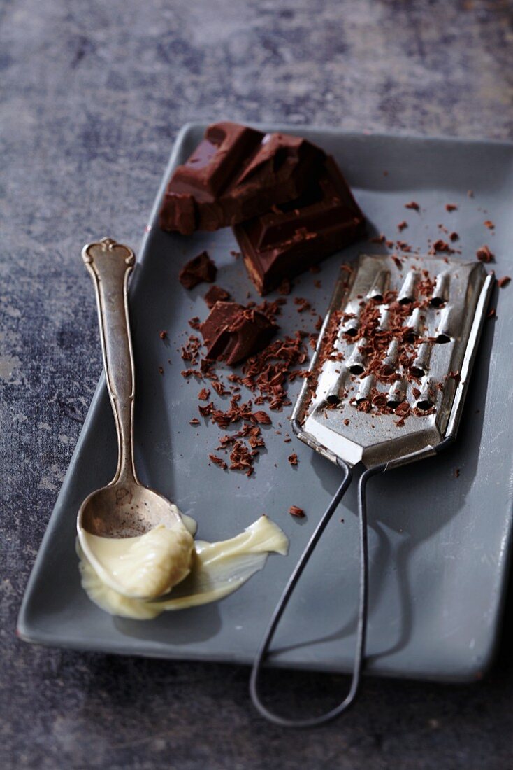 Flüssige weiße Schokolade auf Löffel und dunkle Blockschokolade mit Reibe