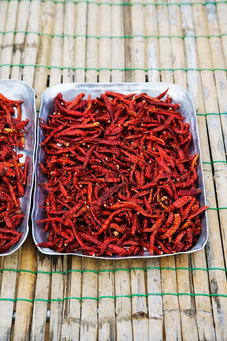 Getrocknete rote Chilischoten in Aluschalen auf Markt (Thailand, Asien)
