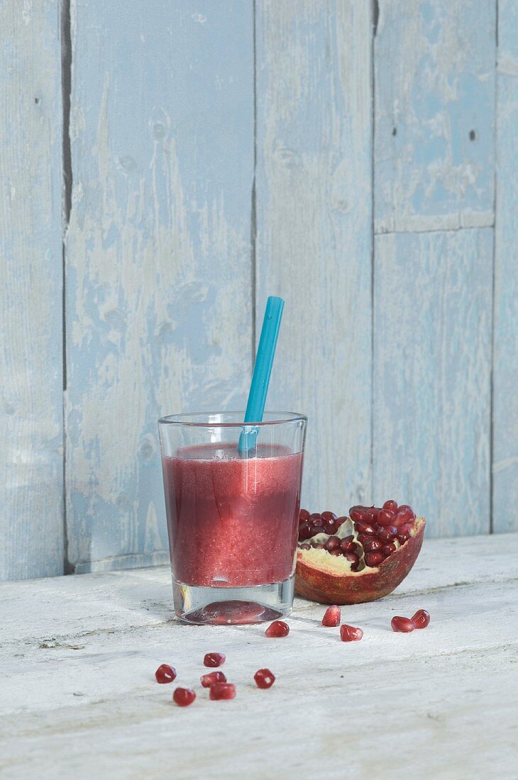 A pomegranate smoothie in a glass with a straw
