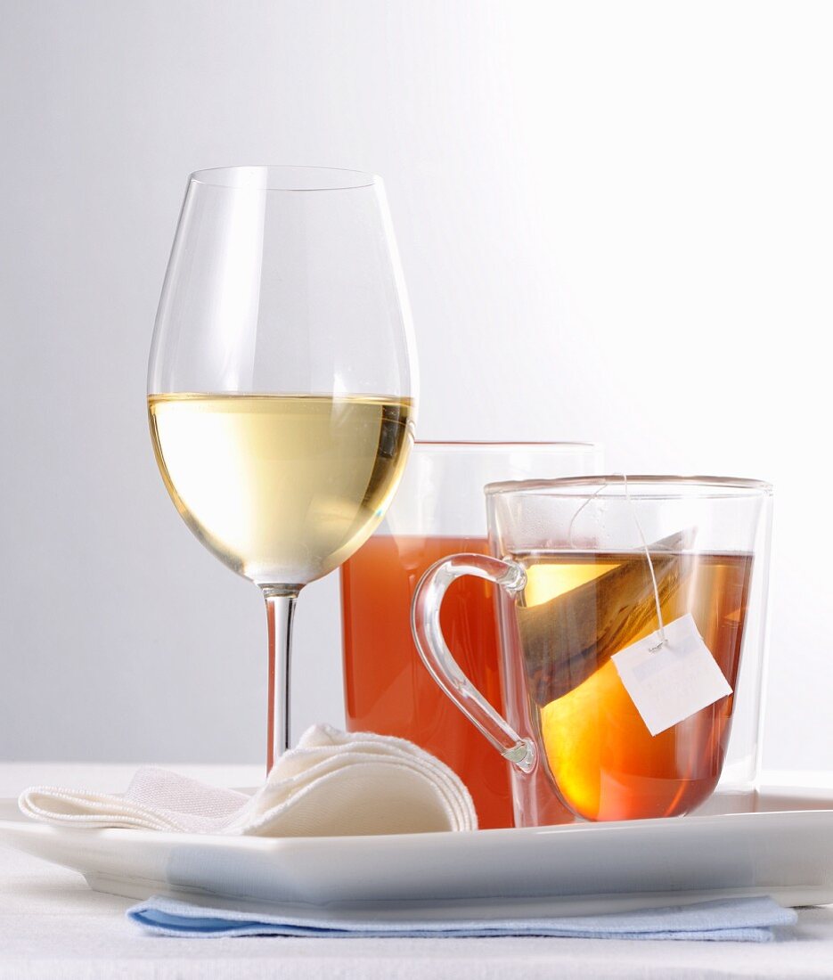 Stillleben mit Weissweinglas, Orangensaft und Tee im Glas