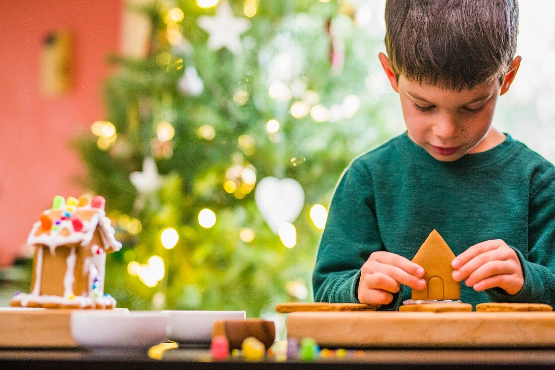 A little boy building a gingerbread house