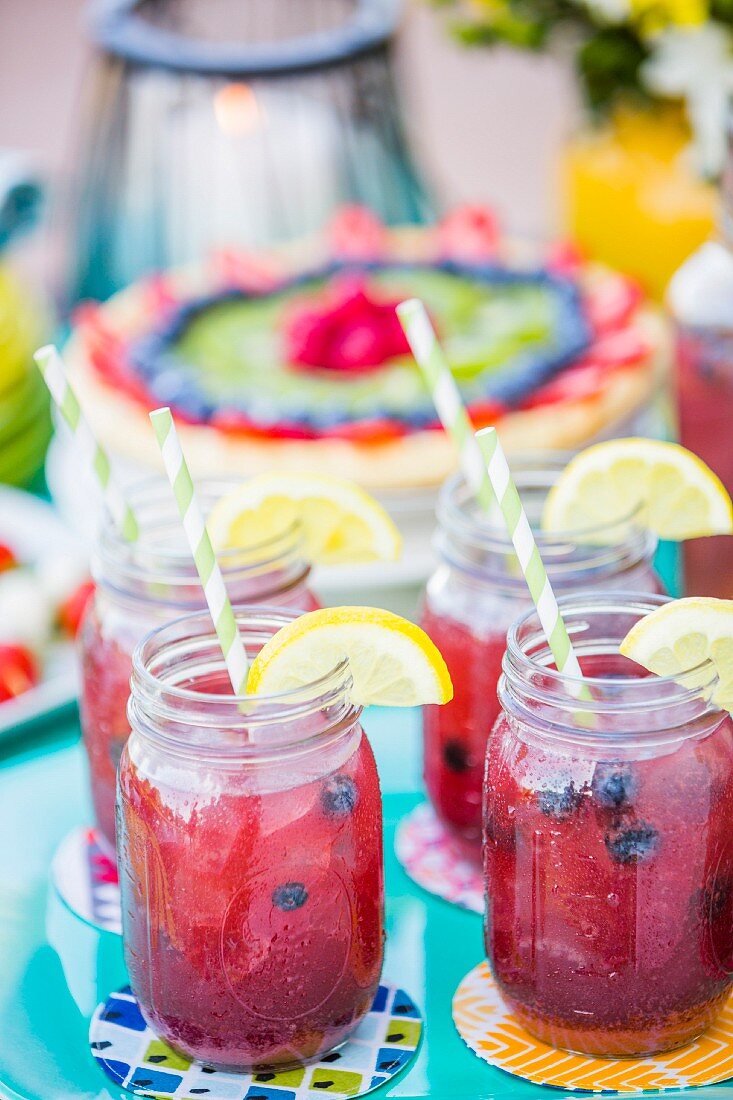 Sommerliche Fruchtsaftgetränke in Gläsern auf Tisch im Freien
