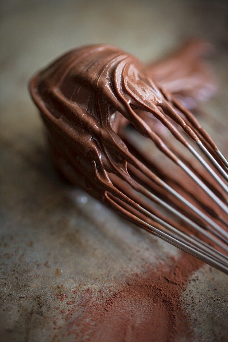 A whisk covered in chocolate glaze
