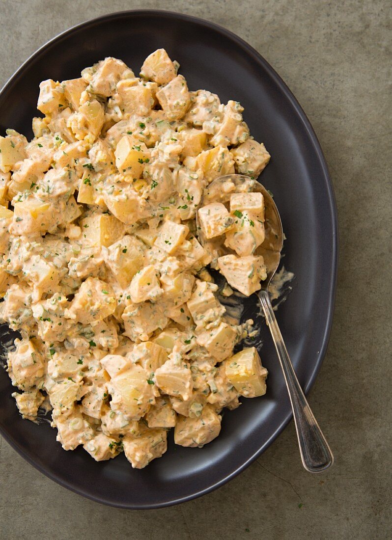 Creole potato salad on a plate with a spoon