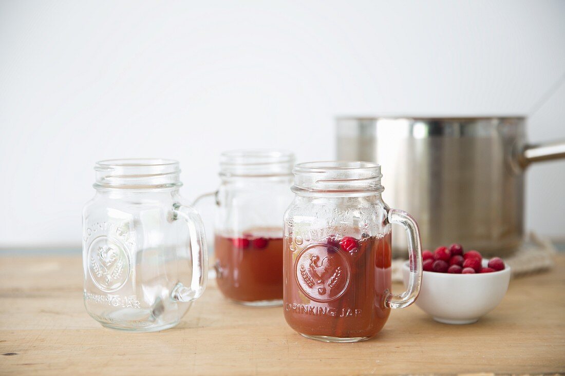 Mulled apple cider with cranberries in glass mugs