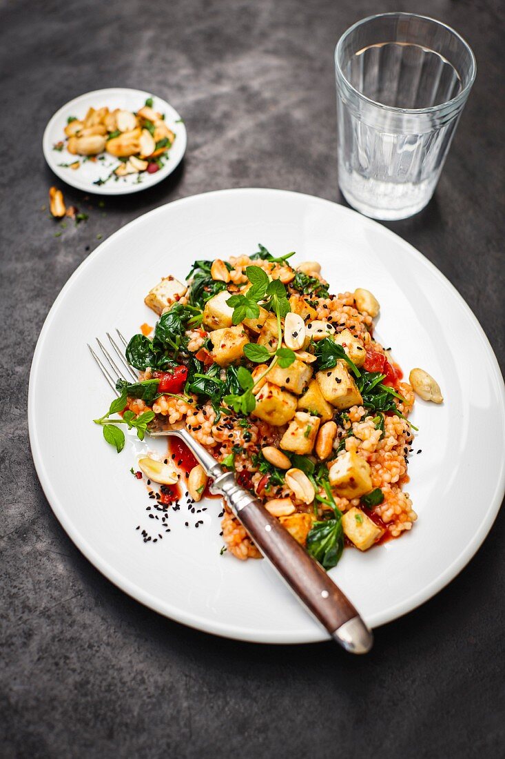 Tomato-infused barley risotto with tofu, peanuts and spinach