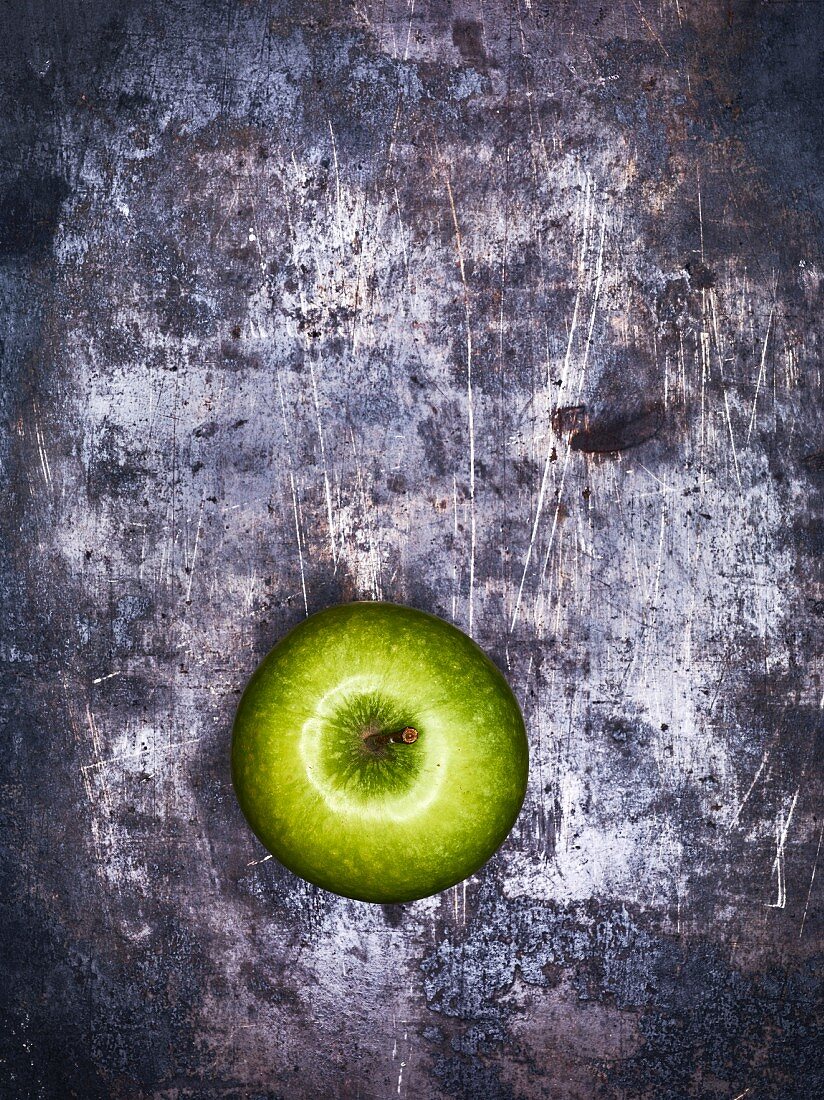 A green apple on a metal surface