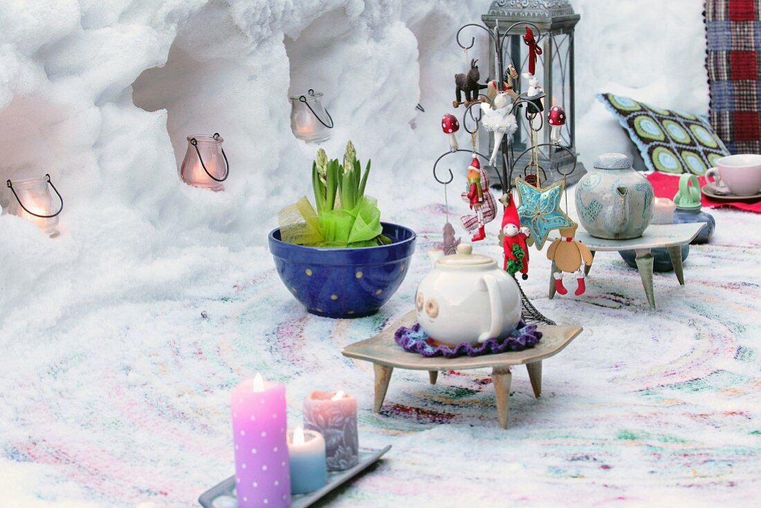Teapots on decorated table in front of candle lanterns in niches sculpture from snow
