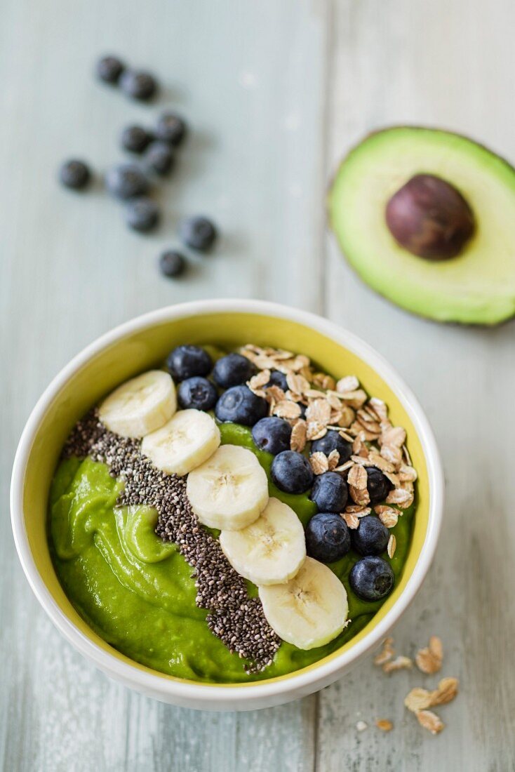 A bowl of smoothie with avocado, banana and blueberries